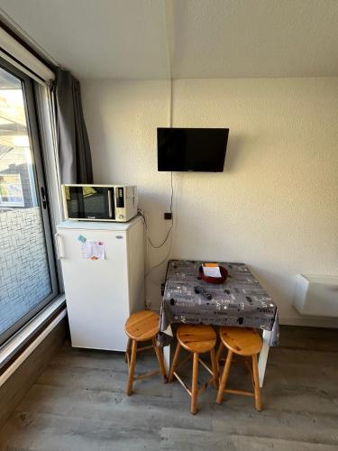 Cette chambre dispose d'une table, de deux chaises et d'un réfrigérateur. dans l'établissement Studio sur Piau Engaly Ramondia, à Le Plan