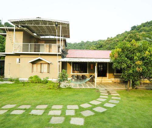 a house with a grass yard in front of it at Malama Stay The Nest Villa 5BHK Kashid in Kashid