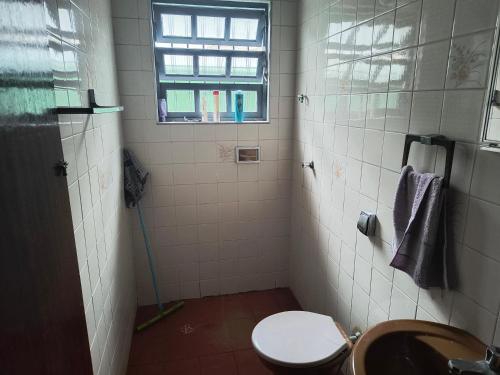 a bathroom with a toilet and a window at Casa de veraneio in Solemar