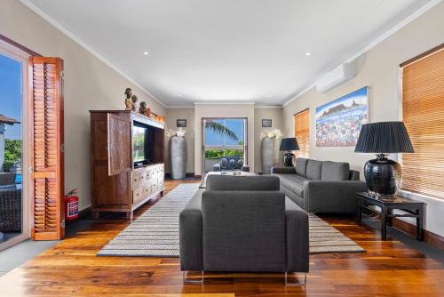 a living room with a couch and a tv at The Cape Bali Luxury Villa with Ocean Views in Camps Bay in Cape Town