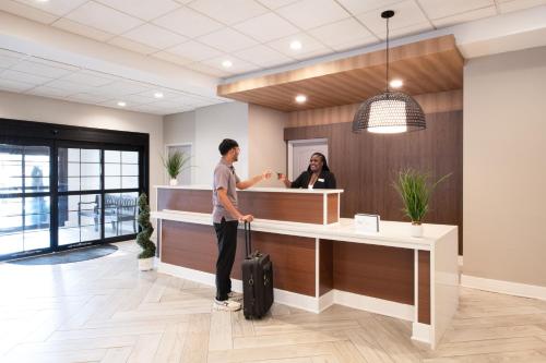 a man with a suitcase standing at a counter in an office at Staybridge Suites Atlanta Airport in Atlanta