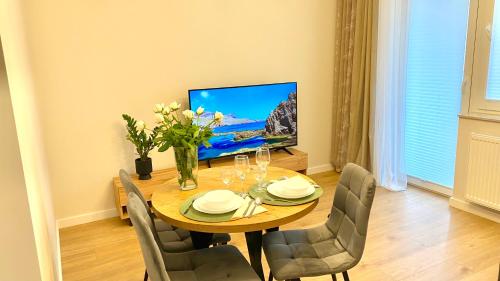 a dining room with a table with chairs and a television at Apartament GREEN CROWNS in Płock