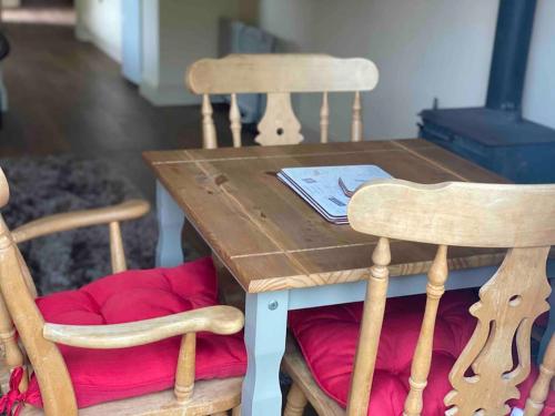 a wooden table with two chairs and a red cushion at Beautiful Cotswold Couples Retreat in Bourton on the Water