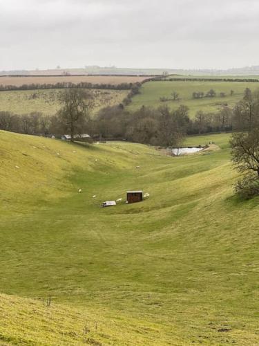 a green field with a barn in the middle of it at Beautiful Cotswold Couples Retreat in Bourton on the Water