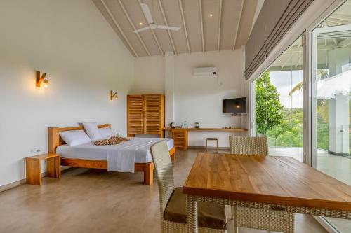 a bedroom with a bed and a wooden table at Samalanka Boutique Hotel in Habaraduwa