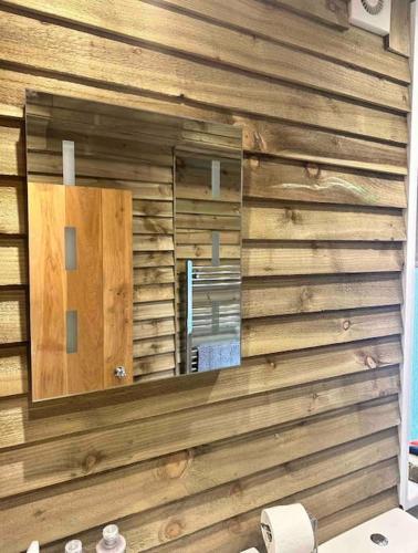 a bathroom with a mirror on a wooden wall at Beautiful Cotswold Couples Retreat in Bourton on the Water