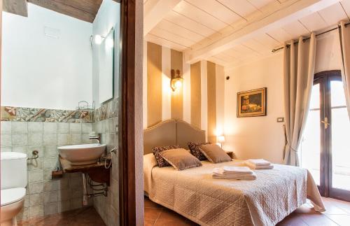 a bedroom with a bed and a bathroom with a sink at Restored Historic Mansion Paterno with Exclusive Pool, Wifi and AC for 20 people in Alghero