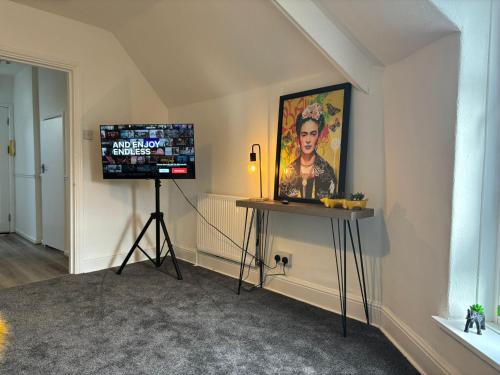 a room with a tv and a table and a painting at Island Heights By MGroupSA in Barry