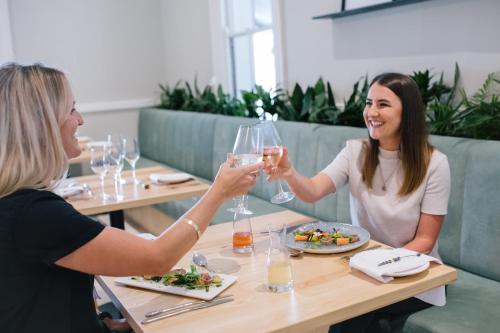 two women sitting at a table with glasses of wine at Hotel Olivewood in East London