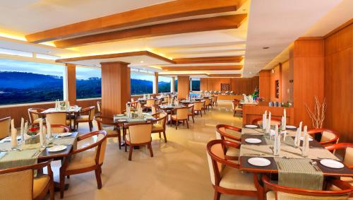 un restaurante con mesas y sillas y una gran ventana en Clouds Valley Hotel, en Munnar