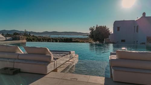a swimming pool with two couches on the side of a house at Sersi Paros Villas & Suites in Kampos Paros