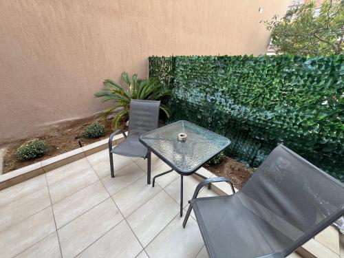 a patio with a table and chairs and a hedge at Peaceful Nook in Alexandroupoli