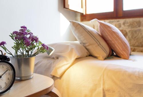 a bed with pillows and a clock on a table at Vistas de ensueño y chimenea - Casa de las Letras in Lledó