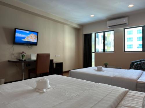 a hotel room with two beds and a flat screen tv at Greenage MingSuite 明绿时代套房 Kota Kinabalu 亚庇市中心 in Kota Kinabalu