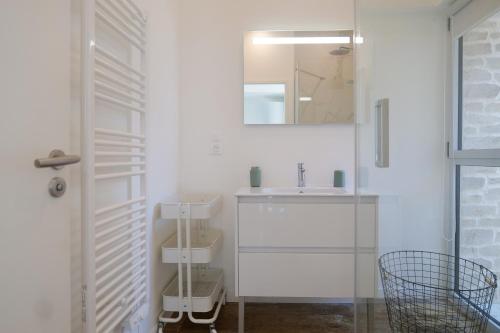 une salle de bain blanche avec un lavabo et un miroir dans l'établissement Maison sablaise rénovée avec goût, idéalement située, proche plage et commerces quartier Arago Les Sables - 6 personnes, à Les Sables-dʼOlonne