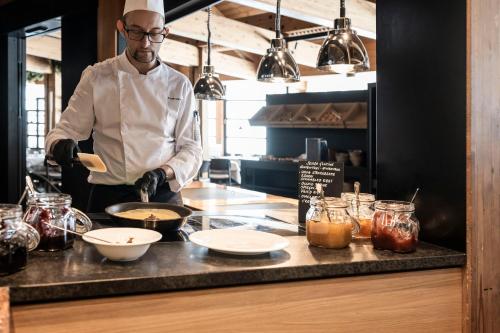 een chef-kok die eten bereidt op een aanrecht in een keuken bij Family Resort Rainer Sexten in Sesto