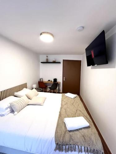- une chambre avec un grand lit blanc et une télévision à écran plat dans l'établissement Les chambres de la bastide - 303, à Carcassonne
