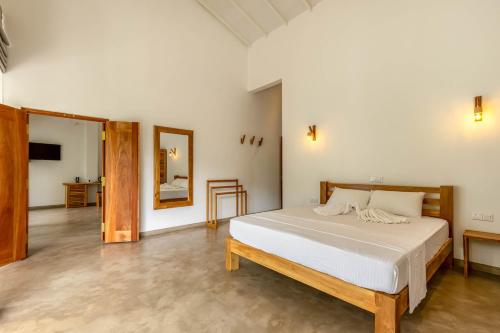 a bedroom with a large bed and a mirror at Samalanka Boutique Hotel in Habaraduwa