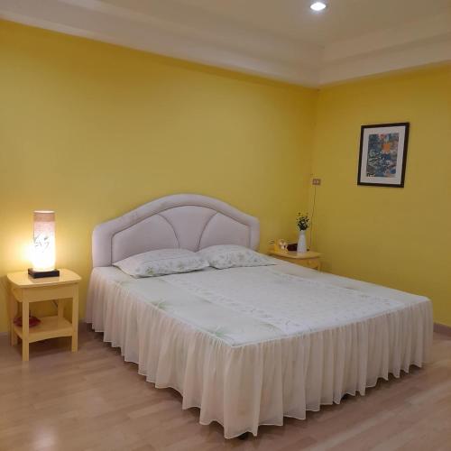 a bedroom with a white bed and a yellow wall at Sport Villa Condo in Hua Hin