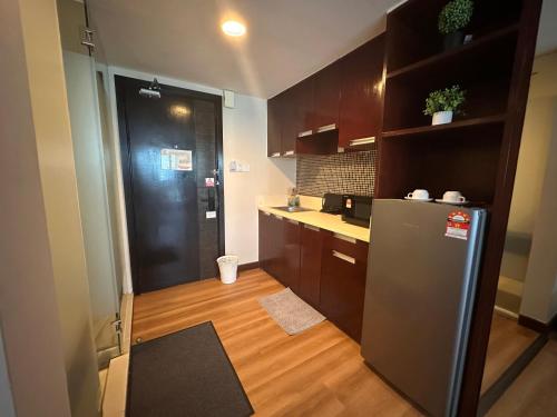 a kitchen with a stainless steel refrigerator and wooden cabinets at Greenage MingSuite 明绿时代套房 Kota Kinabalu 亚庇市中心 in Kota Kinabalu