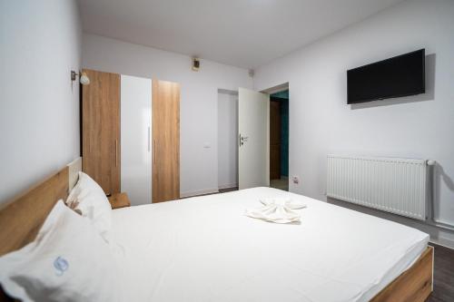 a bedroom with a white bed and a flat screen tv at Vila duMio in Eforie Nord