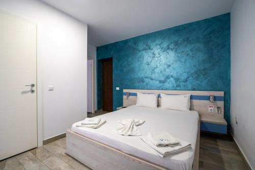 a bedroom with a white bed with a blue wall at Vila duMio in Eforie Nord