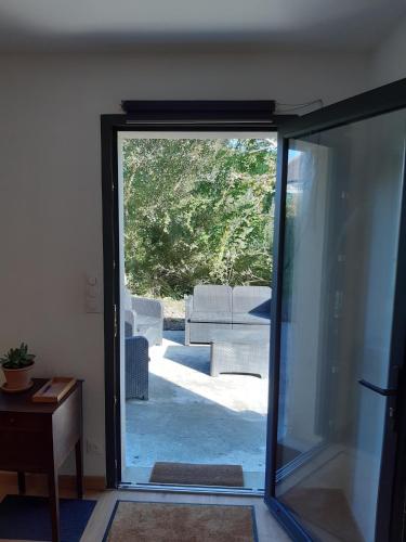 une porte coulissante en verre menant à une terrasse avec un canapé. dans l'établissement F2 Centre Bourg à 10min GR34 et plages, à Lampaul-Plouarzel