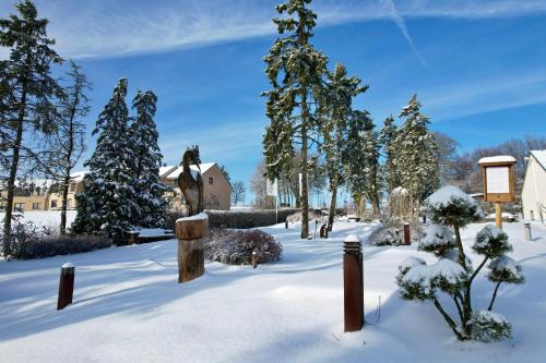 a garden covered in snow with trees and a statue at Holiday Park La Sapinière in Hosingen