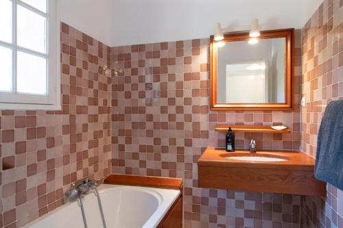 une salle de bain avec une baignoire, un lavabo et un miroir dans l'établissement Le merle, à Cogolin