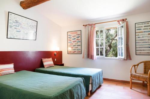 deux lits dans une chambre avec une fenêtre dans l'établissement Le merle, à Cogolin