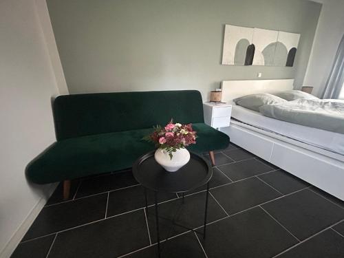 a living room with a green couch and a table with flowers at Ferienwohnung Grüner Friese in Ihlow