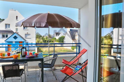 un balcon avec une table, des chaises et un parasol dans l'établissement LocaLise - B02- Appartement vue mer - Plage et centre à pied - Balcon - Wifi inclus - Draps inclus - Animaux bienvenus, à Tréffiagat