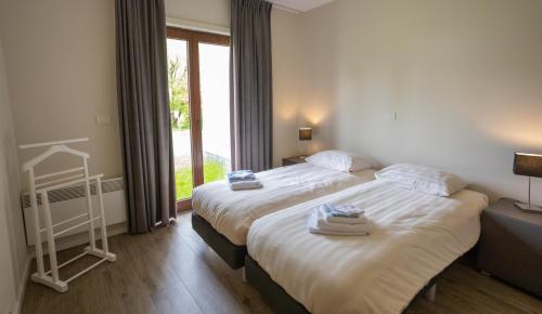a hotel room with two beds and a window at Holiday Park La Sapinière in Hosingen