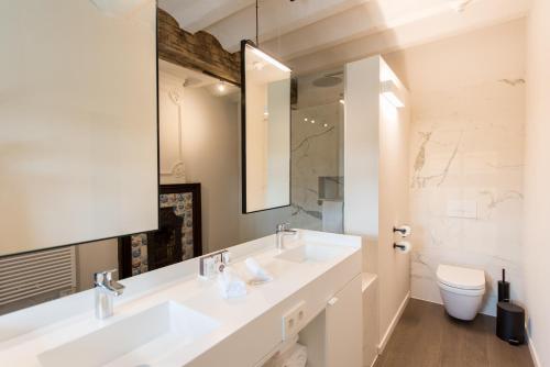 a bathroom with two sinks and a mirror and a toilet at Martin's Rentmeesterij in Bilzen