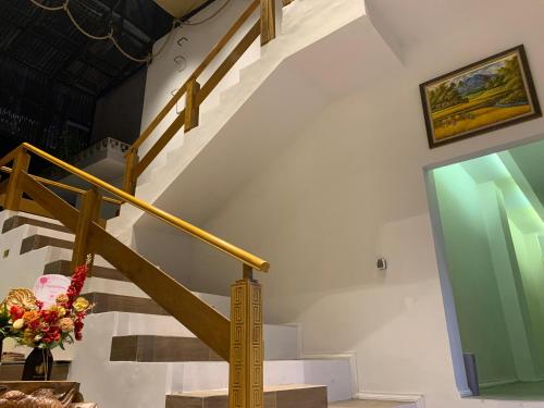 a staircase with a yellow rail and a vase of flowers at Urbanview House of IKIGAI in Madiun
