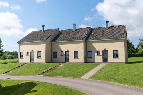 a house on a green lawn with a road at Holiday Park La Sapinière in Hosingen