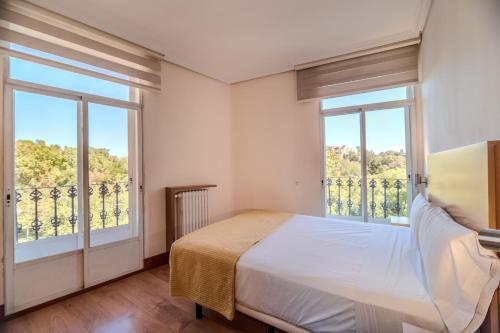 a bedroom with a bed and two large windows at ITC Mora by Soho Boutique in Madrid