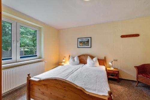 a bedroom with a bed with white sheets and two windows at Krüseliner Mühle - Ferienwohnungen in Krüselin