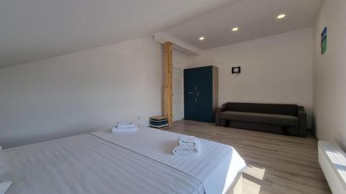 a bedroom with a large white bed and a couch at Vila duMio in Eforie Nord
