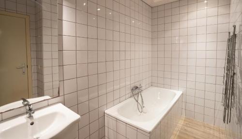 a white tiled bathroom with a sink and a tub at Holiday Park La Sapinière in Hosingen
