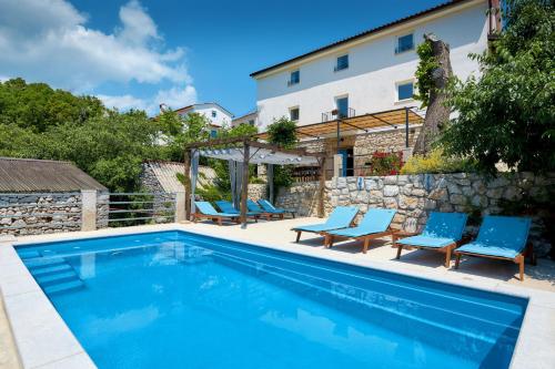 a swimming pool with blue chairs and a building at Villa Eugenia for 8 people with private pool & large garden only 3 km from the beach in Mošćenička Draga