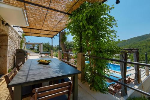 a table on a balcony with a view of a pool at Villa Eugenia for 8 people with private pool & large garden only 3 km from the beach in Mošćenička Draga
