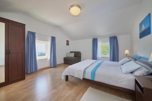 a bedroom with a bed with blue curtains and a chair at Villa Eugenia for 8 people with private pool & large garden only 3 km from the beach in Mošćenička Draga