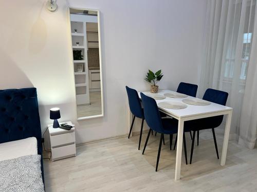 un comedor con una mesa blanca y sillas azules en Dave Apartman 3, en Szeged