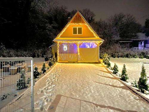 a small yellow house with lights in the snow at Molla Villa Kökény in Kökény