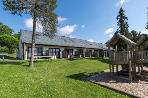 a building with benches in front of a yard at Holiday Park La Sapinière in Hosingen