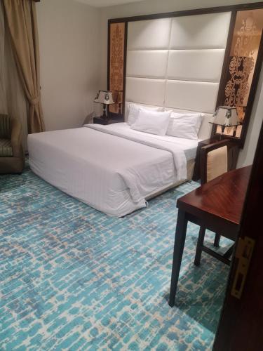 a bedroom with a large white bed and a desk at Makarim Palm Hotel in Rabigh
