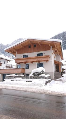 a house with snow on the ground next to a road at Hoamatl, Appartement in Tux