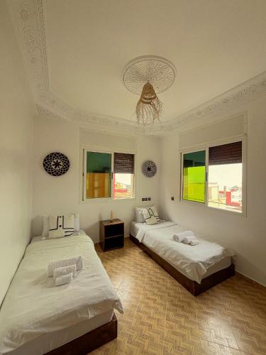 Un dormitorio con dos camas y una lámpara de araña. en cactus surf experience, en Imsouane