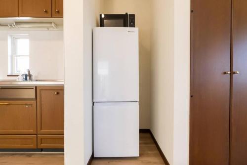 a white refrigerator with a microwave on top of it in a kitchen at ジブリパークまで車10分 遊べるキッズハウス1棟貸切り 敷地内無料駐車場あり 最大12名 in Seto